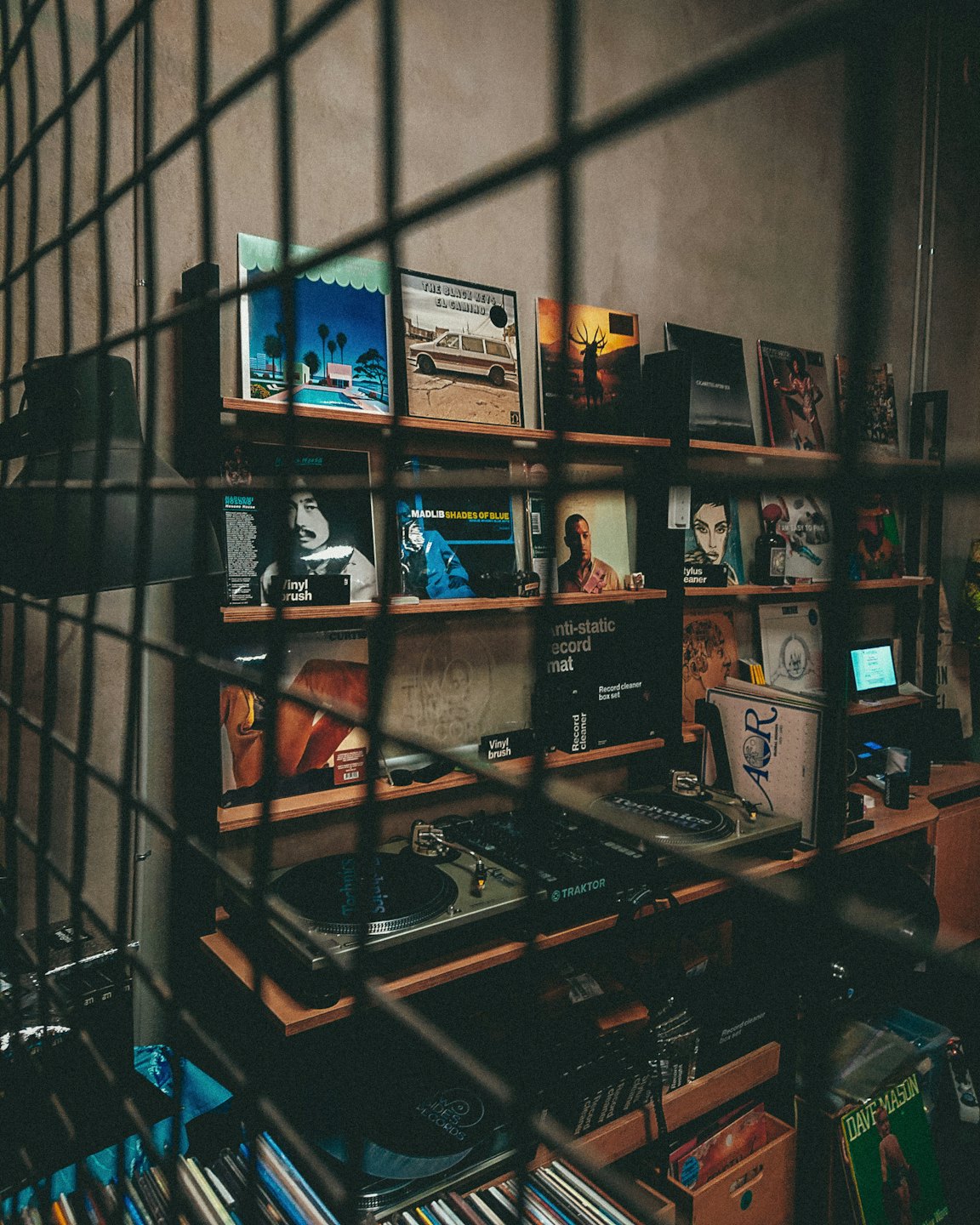 Vinyl records and DJ equipment displayed on wooden shelves.