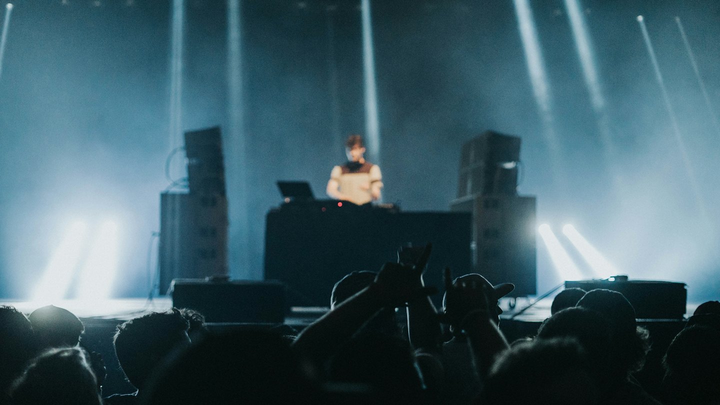 DJ performs on stage in front of a cheering crowd.