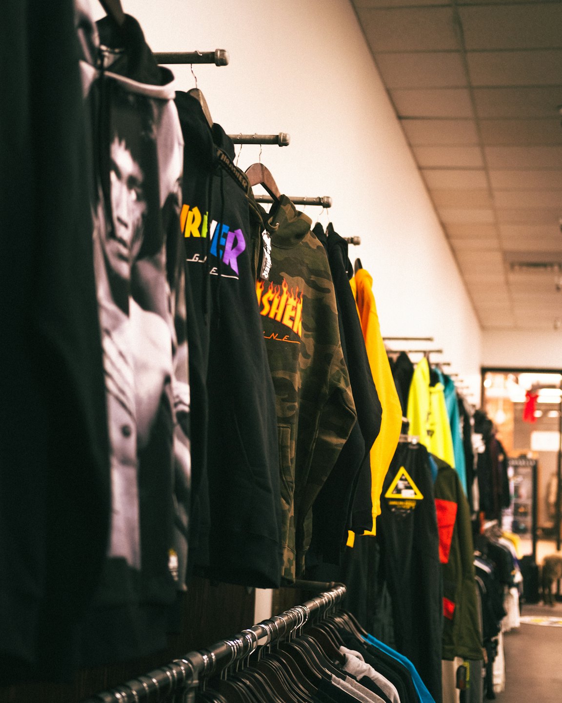 Streetwear hoodies hang on a rack in a retail store.