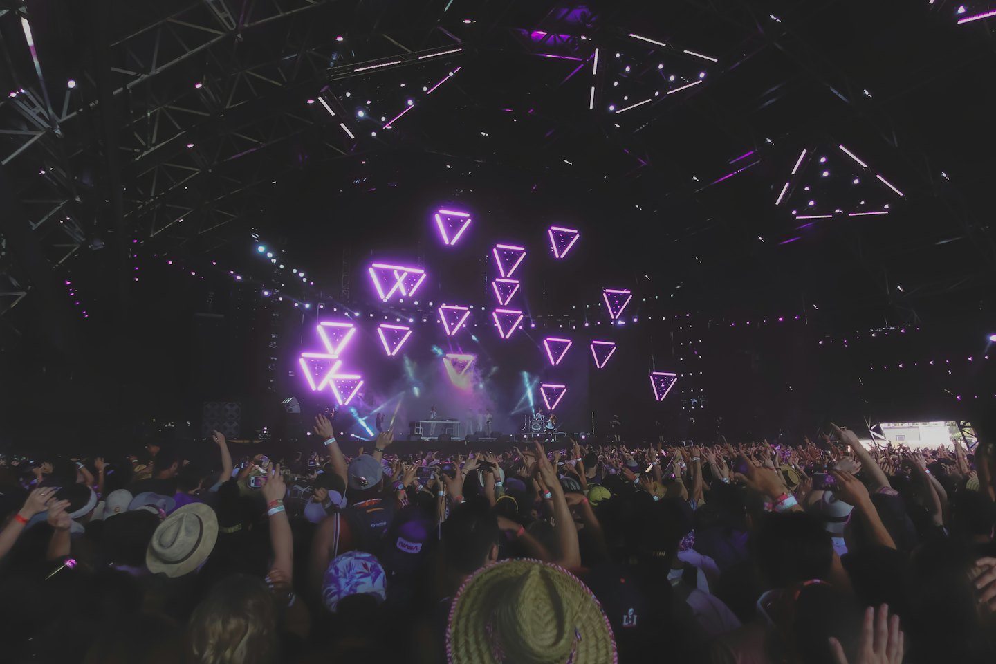 Crowd of fans with raised hands watch a concert performance.